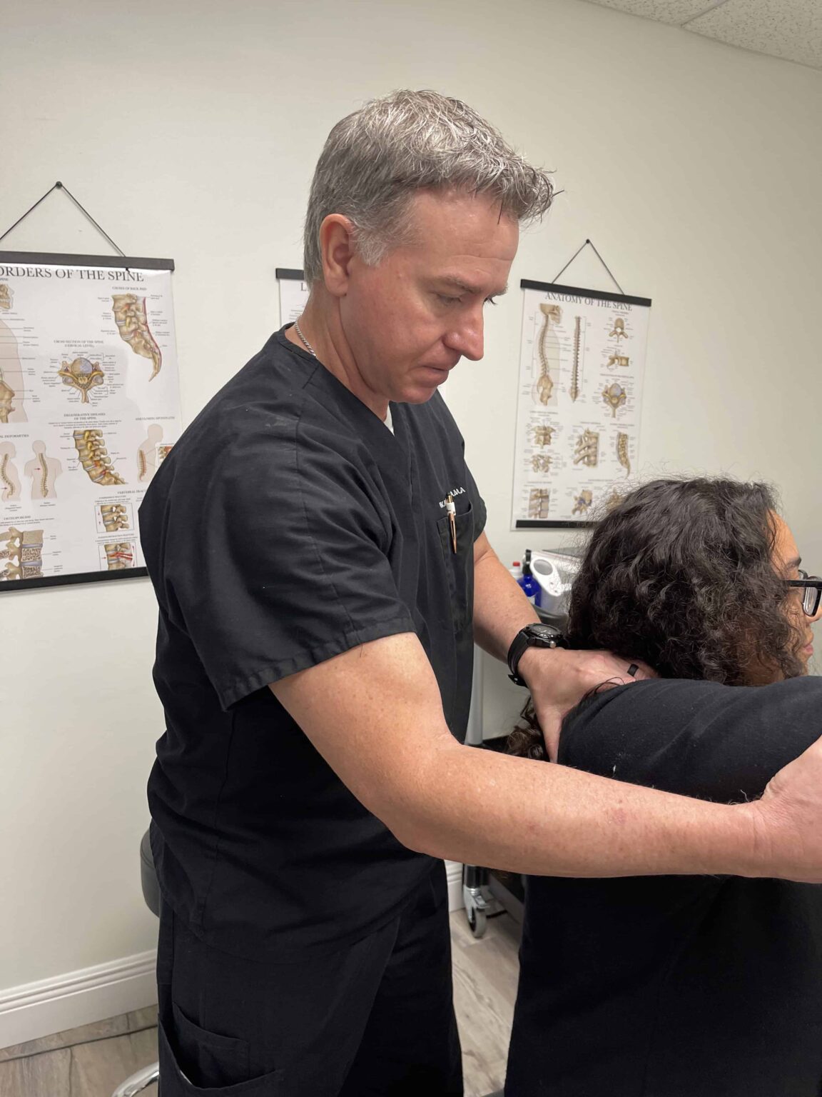 Doctor performing manual adjustment on a patient with a shoulder injury at a rehabilitation clinic