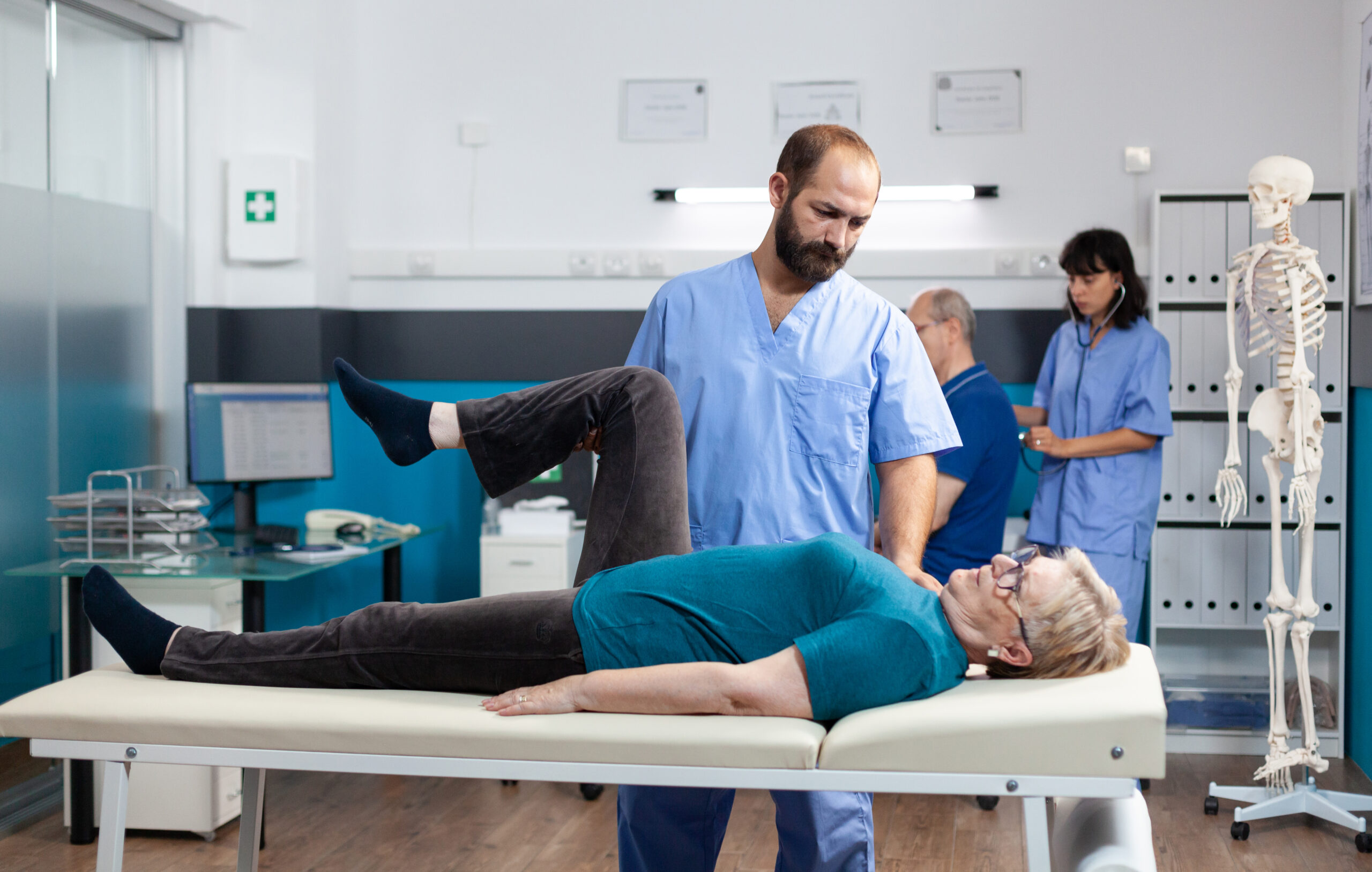 Physical therapist assisting an older adult with a bent knee exercise during hip rehab in a clinic setting