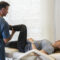 Physical therapist guiding a patient through leg raise mobility during hip rehab on a treatment table