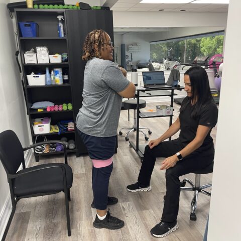 Patient engaging in guided physical therapy exercises with resistance band under the supervision of a therapist at MedAmerica Rehab in Deerfield Beach.