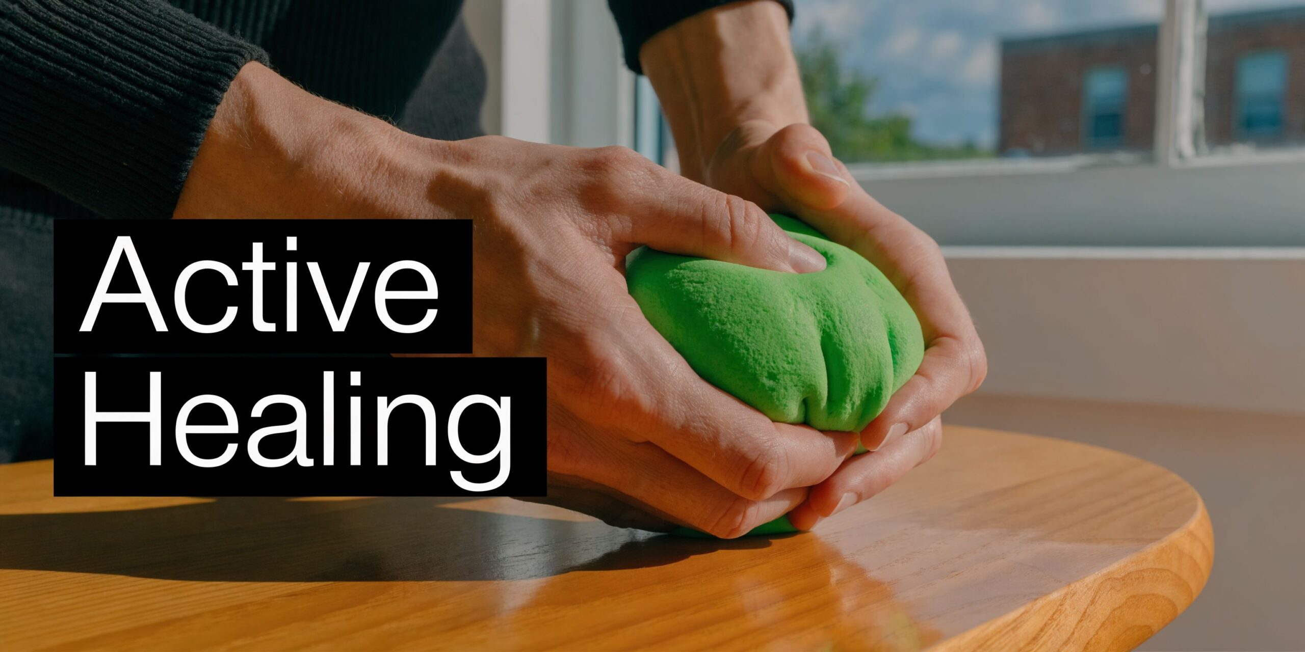 A person uses their hands to squeeze and knead a green ball for physical therapy exercises.