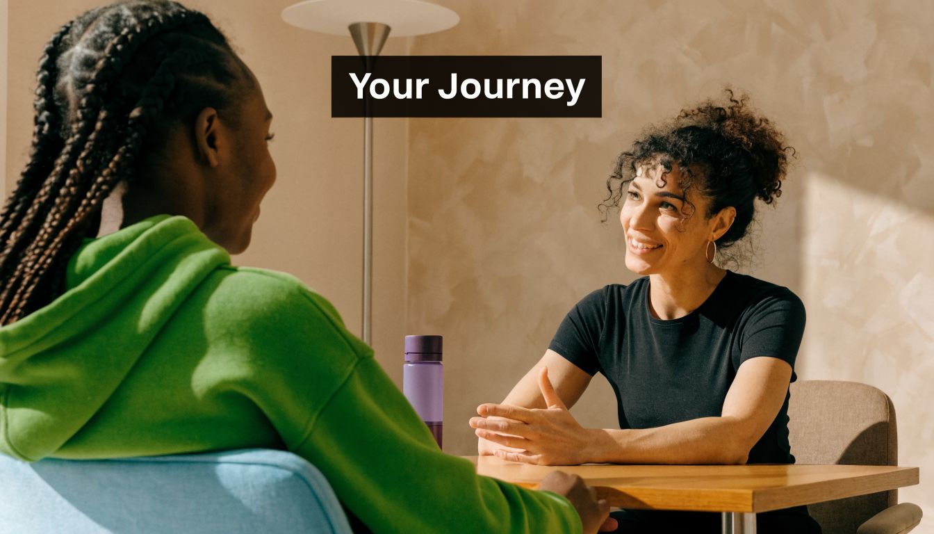 A woman in a green hoodie consults with a therapist in a bright, professional office setting.