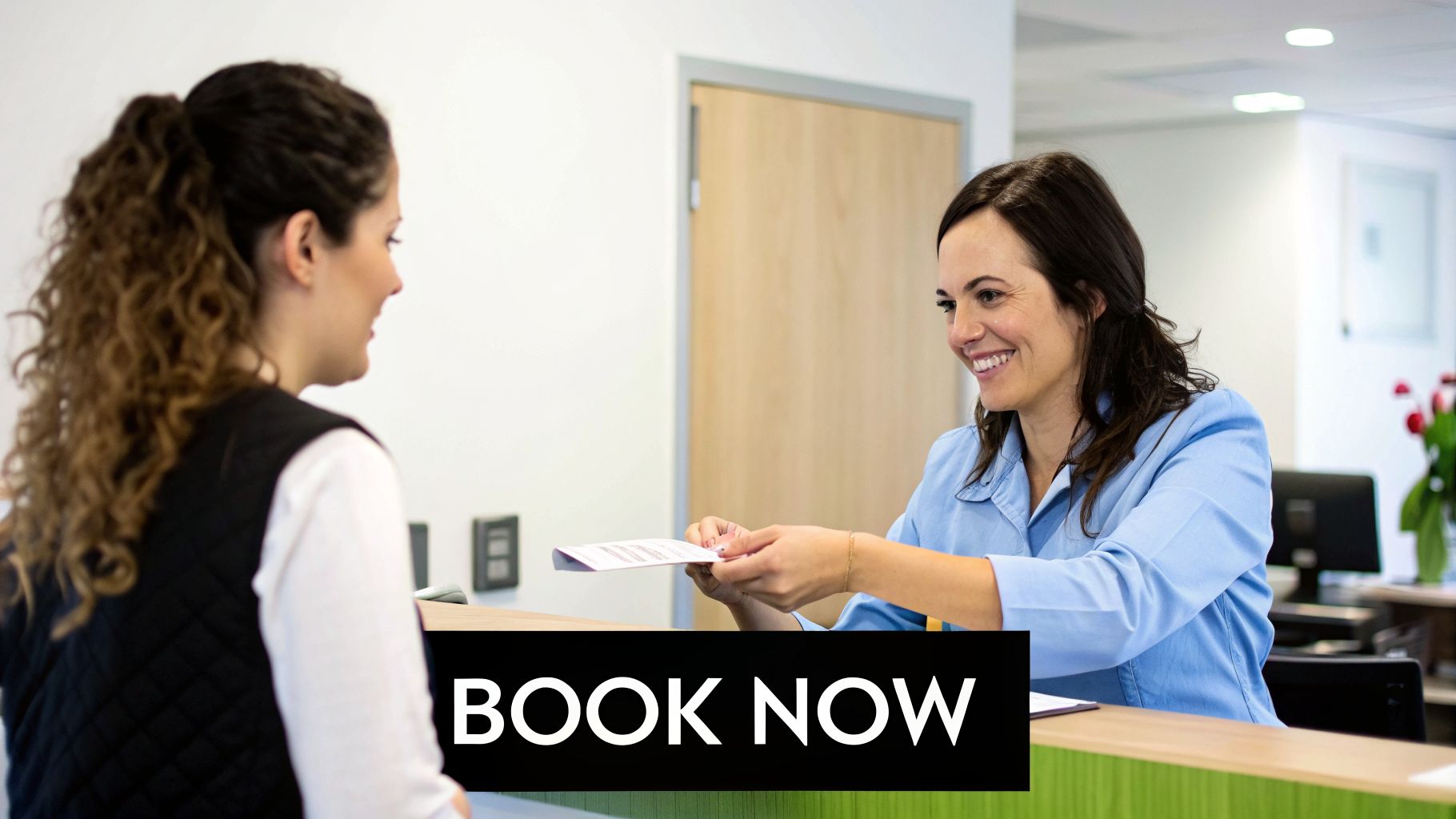 A smiling receptionist hands paperwork to a patient at a modern medical clinic's front desk.