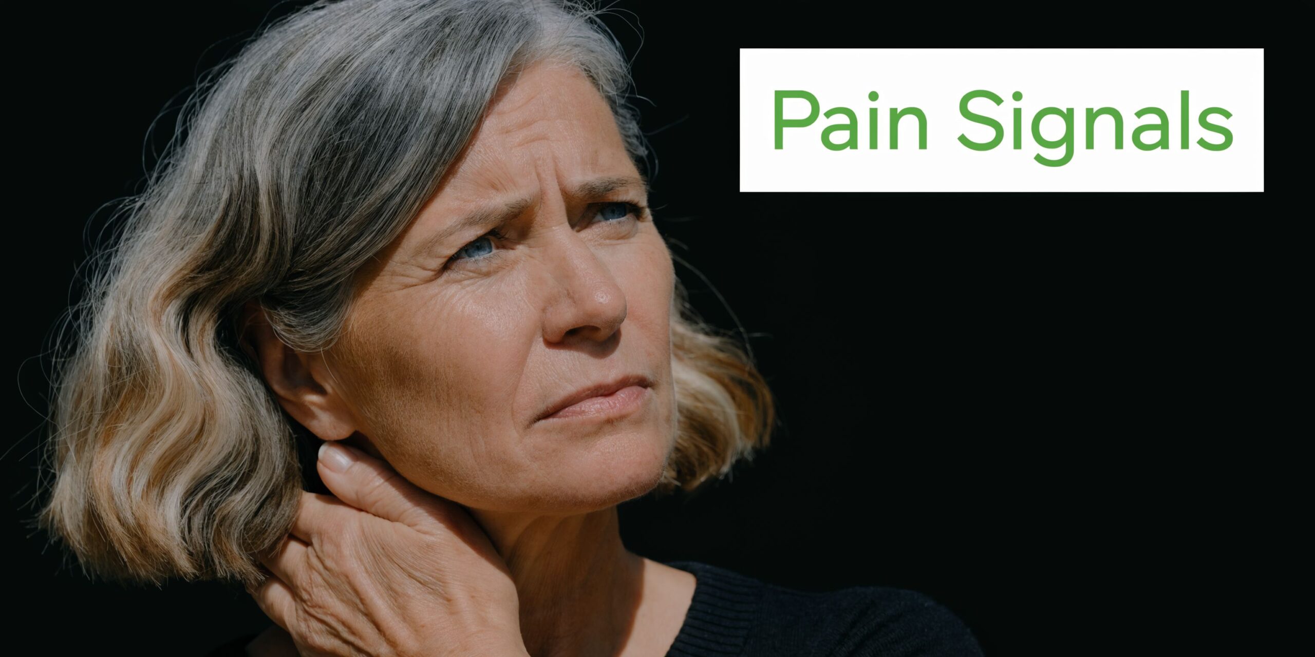 Middle-aged woman with grey hair touching her neck and looking concerned, suggesting cervical spine pain.