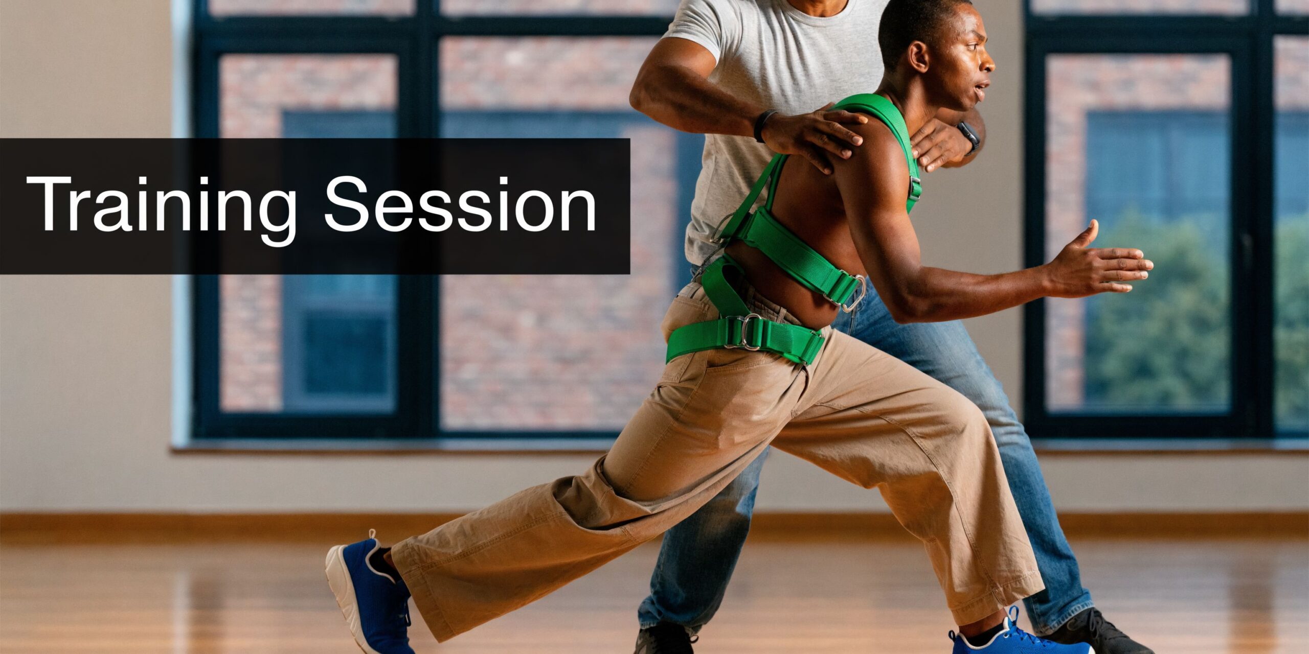 A physical therapist assists a patient during a gait training session using a supportive harness in a studio.