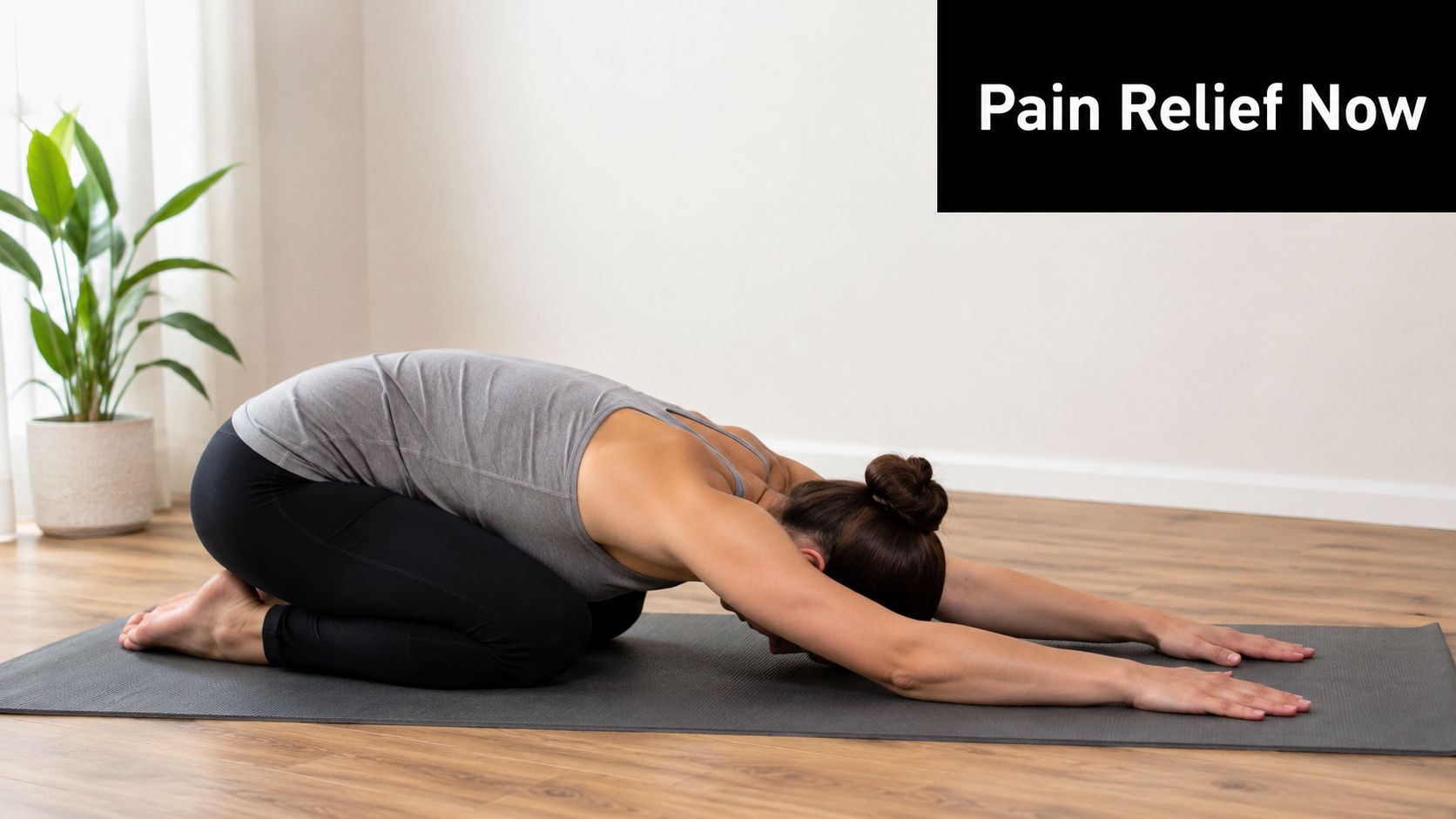 A woman practicing the child's yoga pose on a grey mat in a bright, peaceful room.