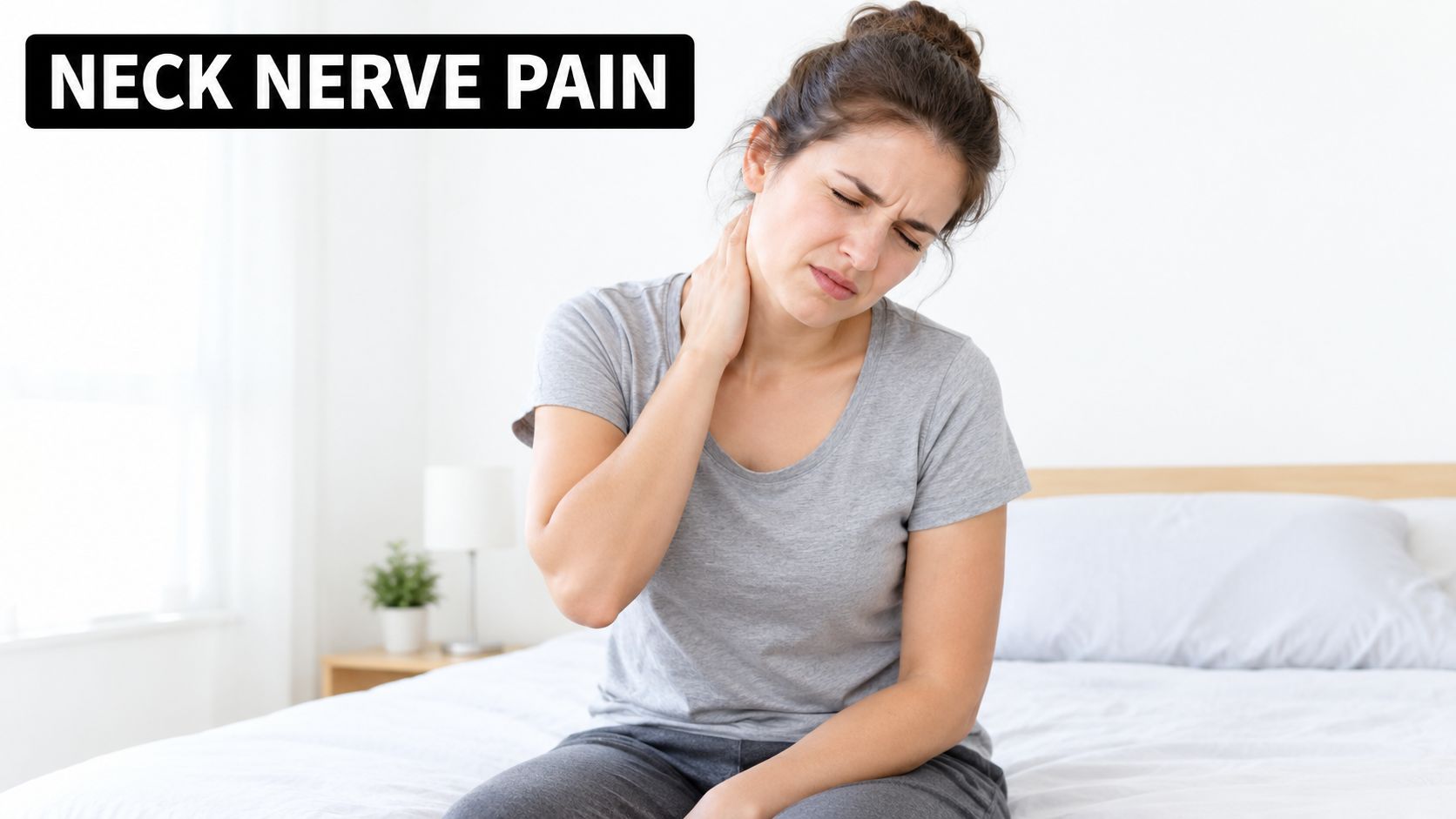 A young woman sitting on a bed looking distressed while holding her painful, stiff neck.